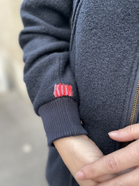 image de manteau adulte en laine avec avec réparation visible et colorée sur le poignet de manche